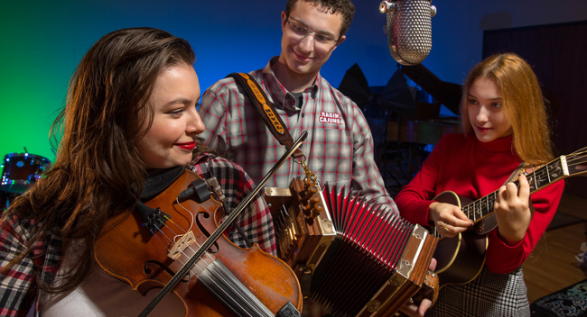 Three Bryman College traditional music students playing in a campus music studio