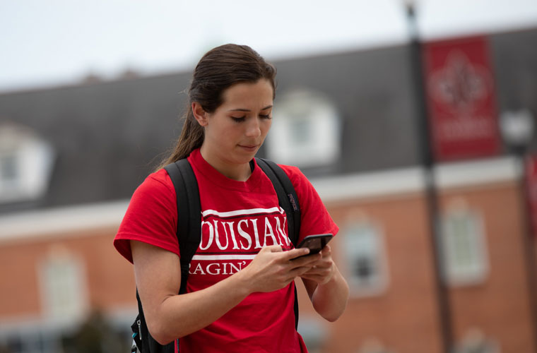 BC student walking through the Quad while looking at her phone