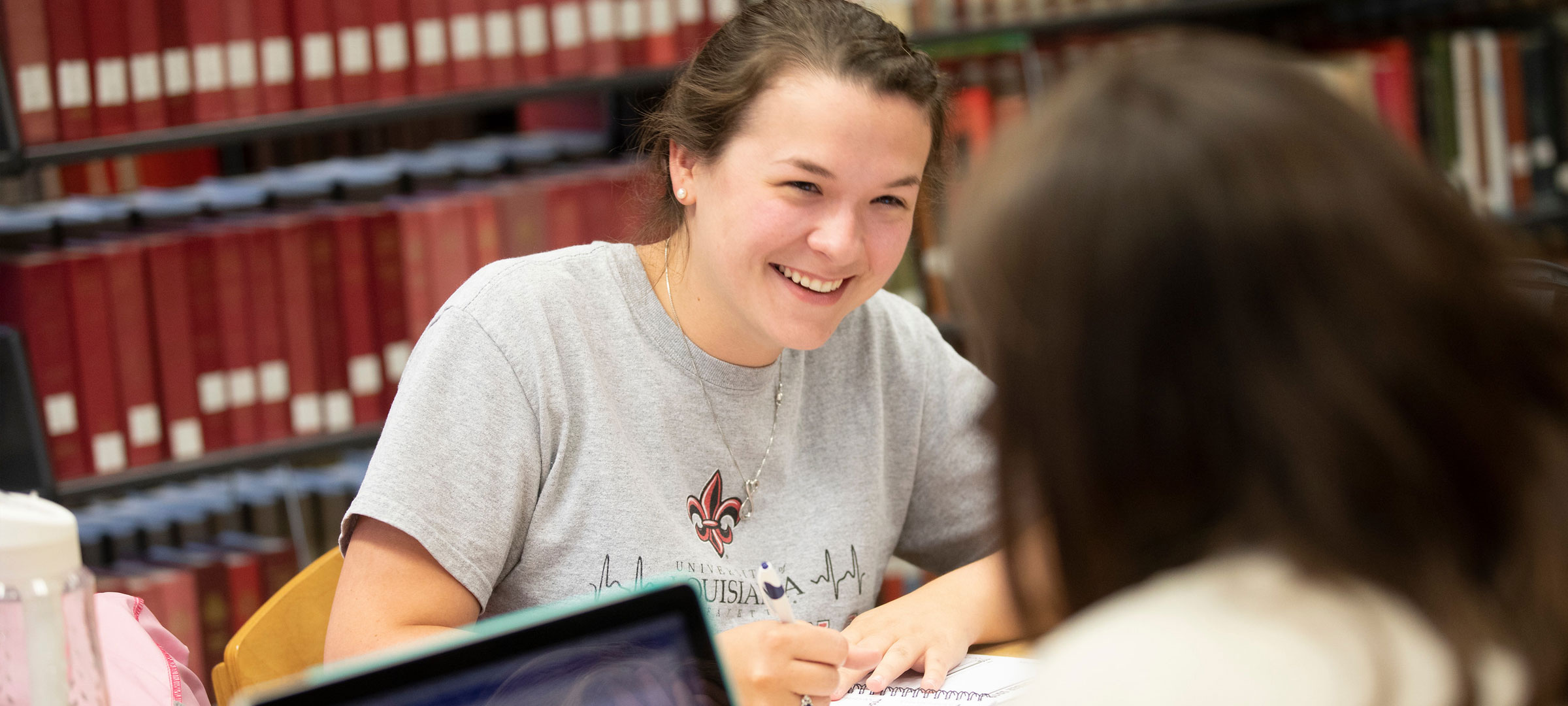 A Bryman College student smiling and laughing with a classmate while studying